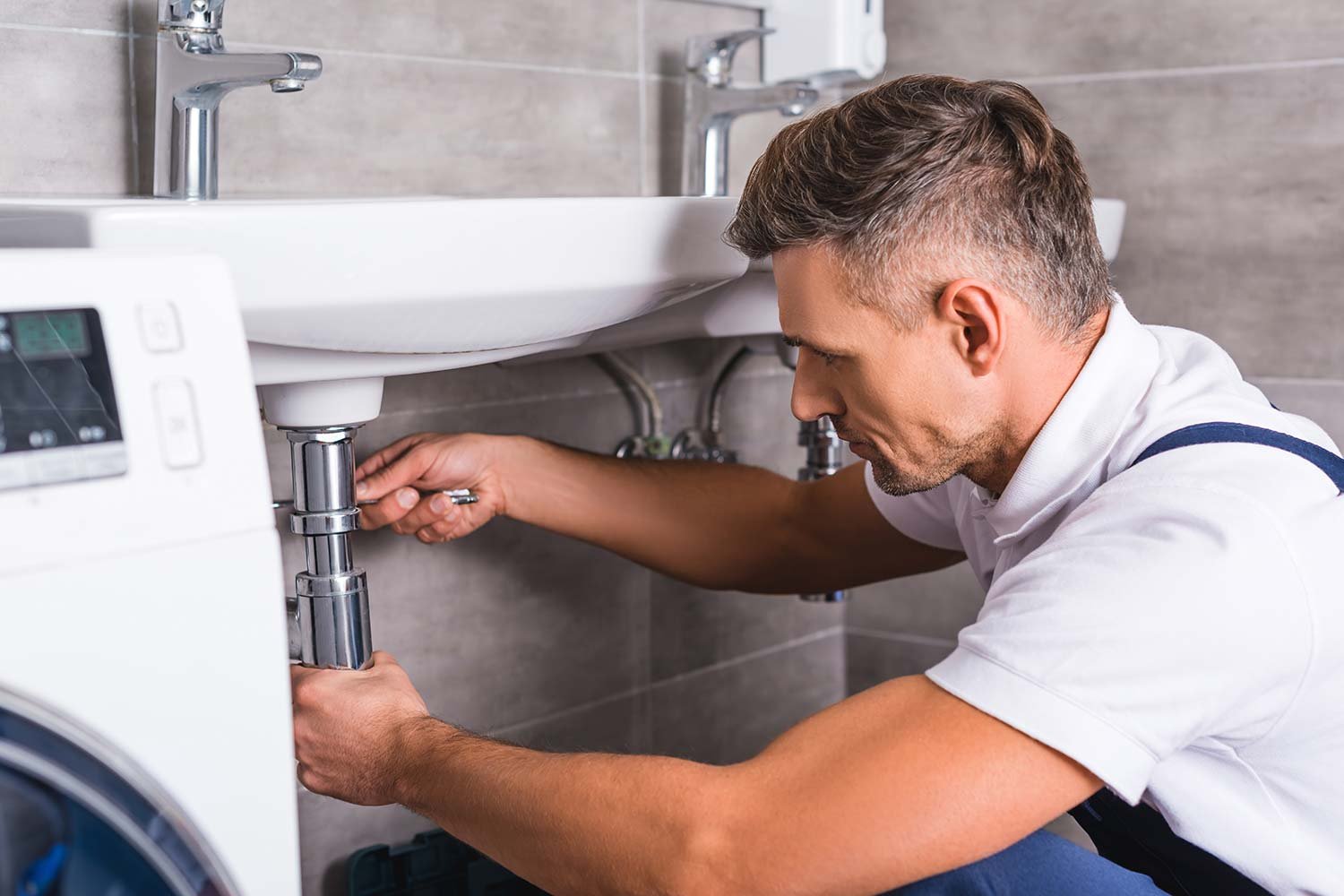 adult plumber fixing sink at bathroom resize 1