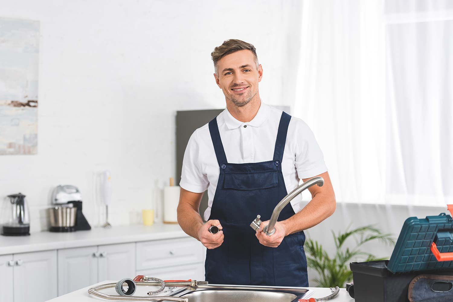 smiling adult repairman taking off kitchen faucet resize