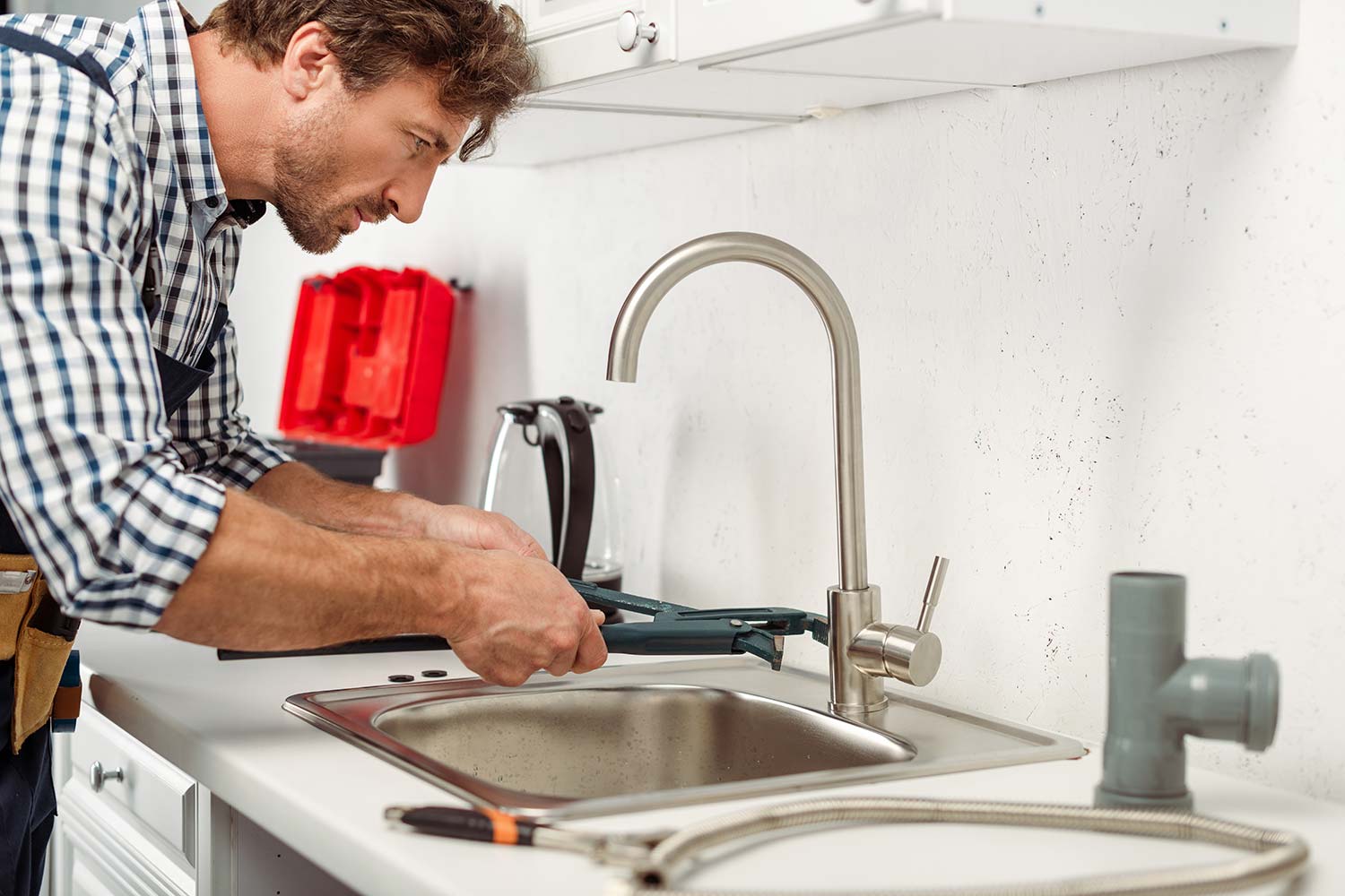 side view of handsome repairman using pipe wrench resize 1